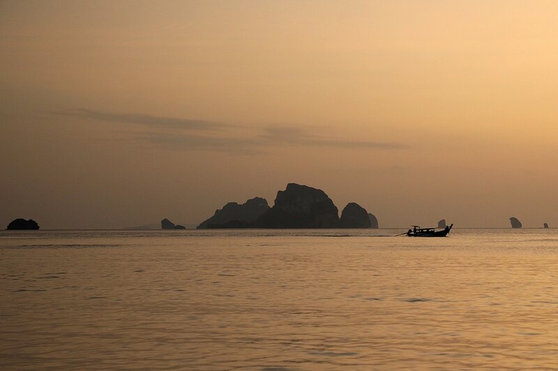Закат на пляже Ао Нанг: острова в дымке и рыбацкая лодка