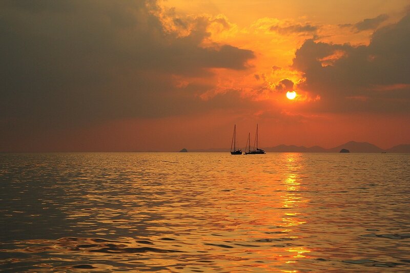 Закат в Андаманском море на пляже Ао Нанг (провинция Краби, Таиланд): солнечная дорожка, яхты, острова и волны