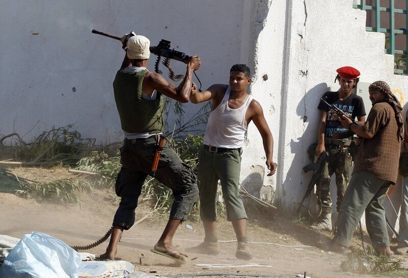 A Libyan rebel fighter fires his machine gun towards a sniper as they make a final push to flush out pro-Gaddafi's forces in Tripoli