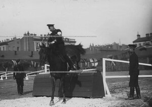 Офицер на лошади берет барьер во время конных состязаний.