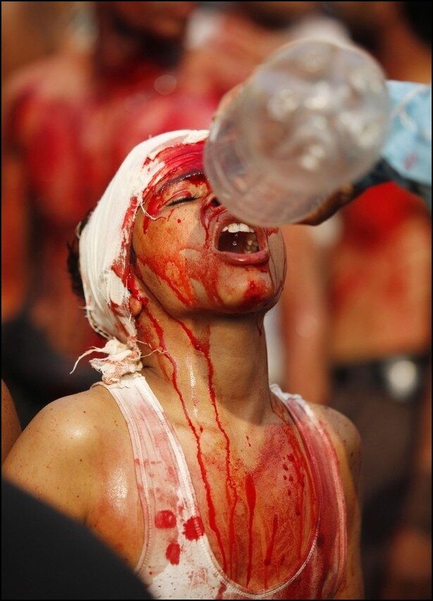 A Shi'ite Muslim boy drinks water as he flagellates himself during an Ashura procession in New Delhi