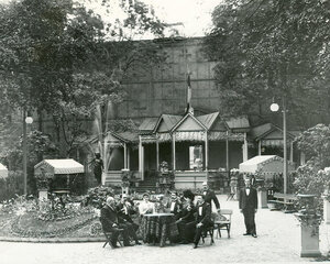 Группа посетителей за столом в саду ресторана Контан (крайний слева сидит владелец ресторана Альмир Жуэн).