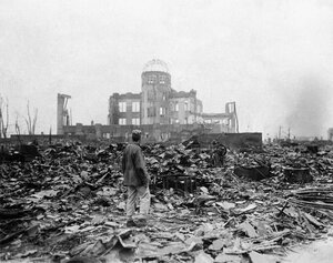 Союзный корреспондент стоит среди руин перед каркасом здания, которое раньше было городским театром, в Хиросиме 8 сентября 1945 года, спустя месяц после того, как первая атомная бомба, когда-либо применявшаяся в военных действиях, была сброшена Соединённы