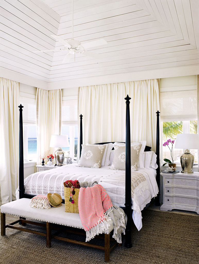 спальня в доме на побережье, кровать со столбиками, белые стены, белый интерьер, плетеный ковер, белые шторы