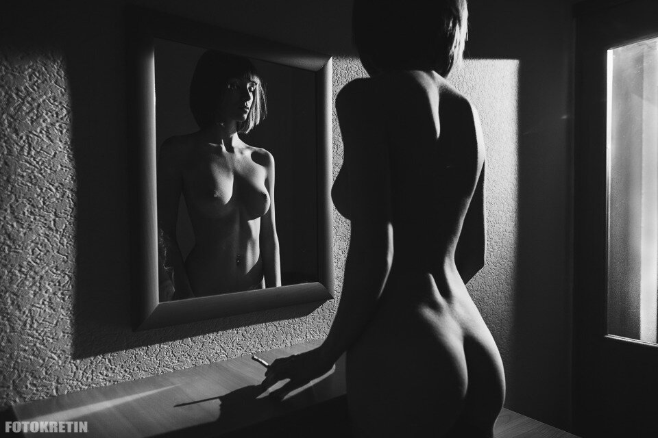 Голая девушка любуется красивой грудью в зеркале