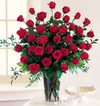 Букет красных роз стоит рядом с окном