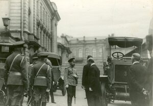 Император Николай II и сопровождающие его лица осматривают новую модель автомобиля у входа в выставочный зал.