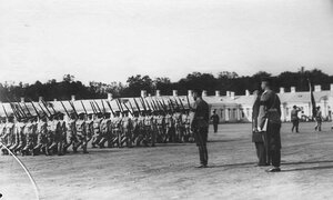 Отряд воспитанников с ружьями на плече проходит мимо императора Николая II .