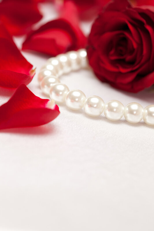 Red roses with  white pearls on white satin background