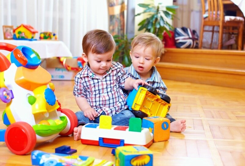 two cute baby toddlers playing in nursery room