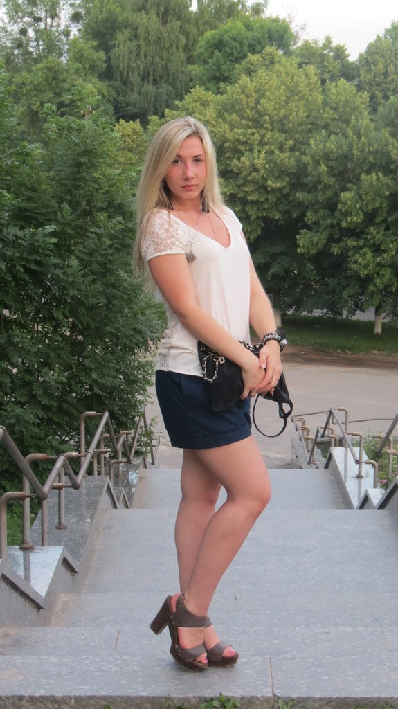 Девушка блондинка в черной юбке на ступеньках