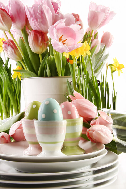 Easter eggs in cups with spring flowers on white