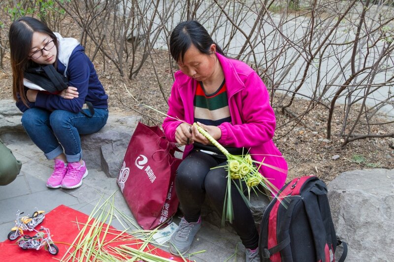 Женщина плетет из травы букет цветов, парк Сяншань, Пекин