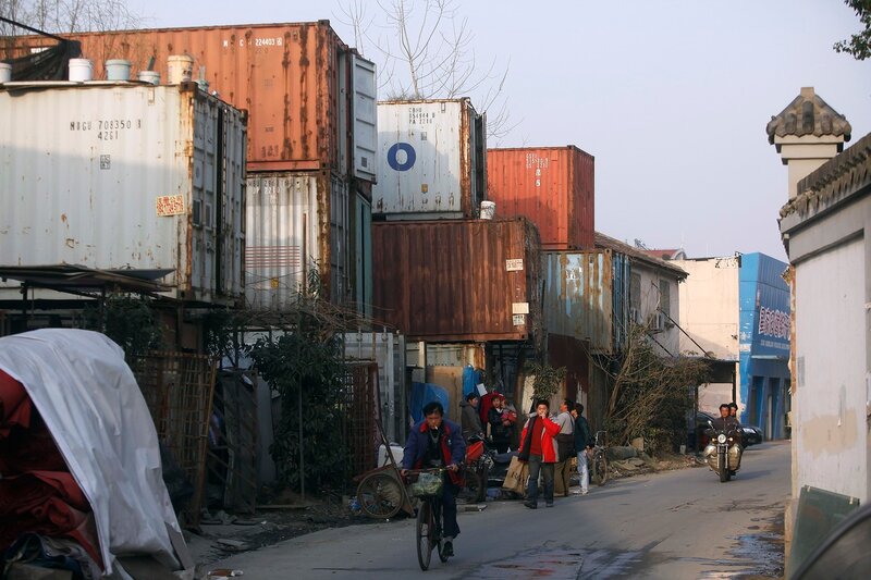 People stand outside shipping containers serving as their accommodation, in Shanghai